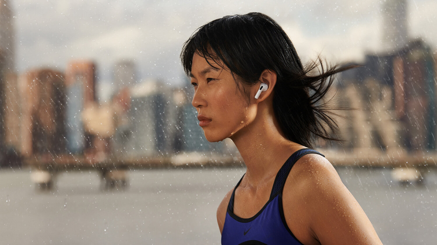 A woman walking in the rain wearing the 3rd-gen Apple AirPods.