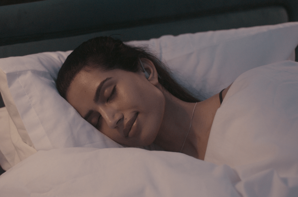 Woman sleeping while wearing the Kokoon Noisebuds.