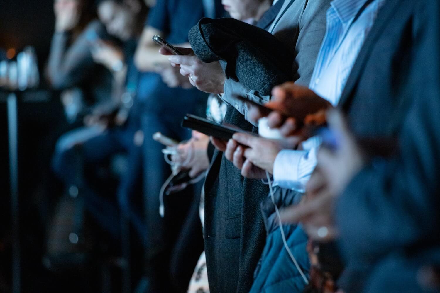 A line of men wearing suits and holding smartphones.