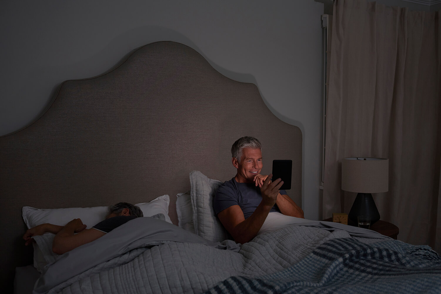 Man reading on an Amazon Kindle in bed in the dark