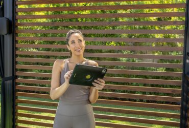 A woman outside on a tablet with a speaker mounted.