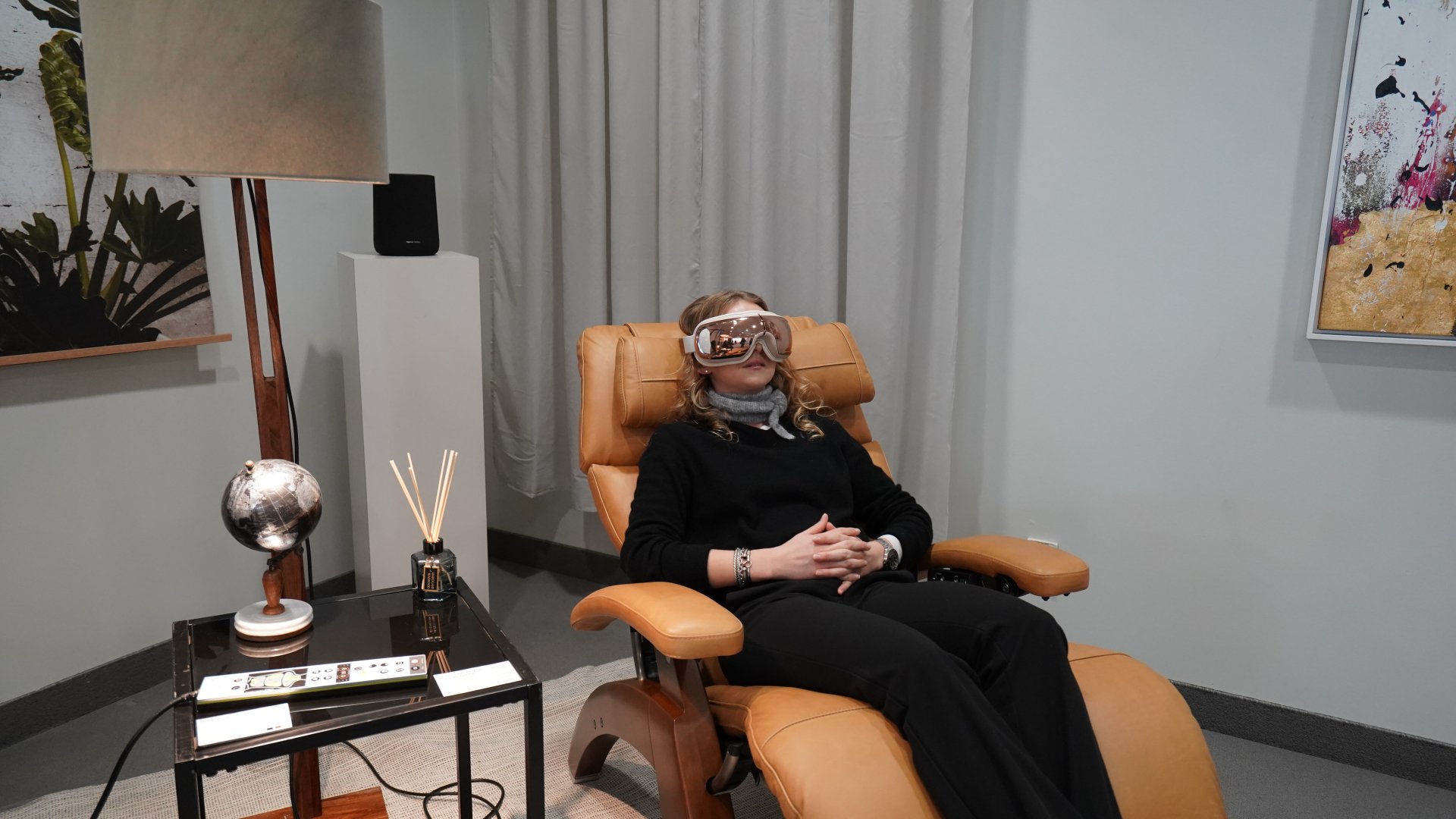 A woman laying back in a chair with a Renpho eye massager.