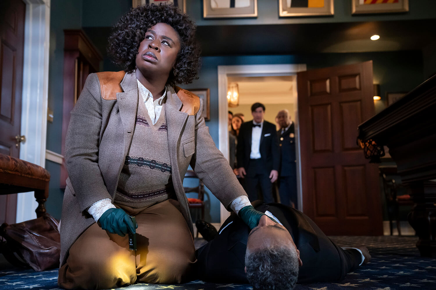 A woman checks a man's pulse on the ground in The Residence
