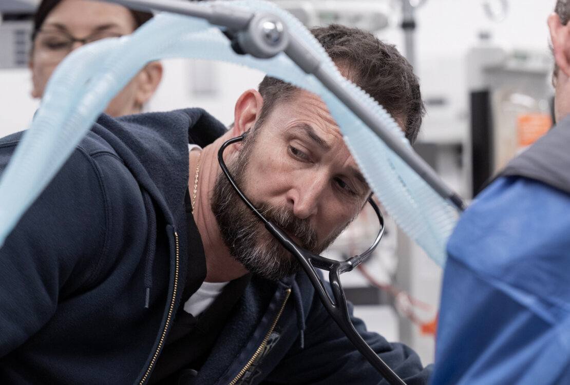 Robby with a stethescope dealing with a patient in The Pitt.