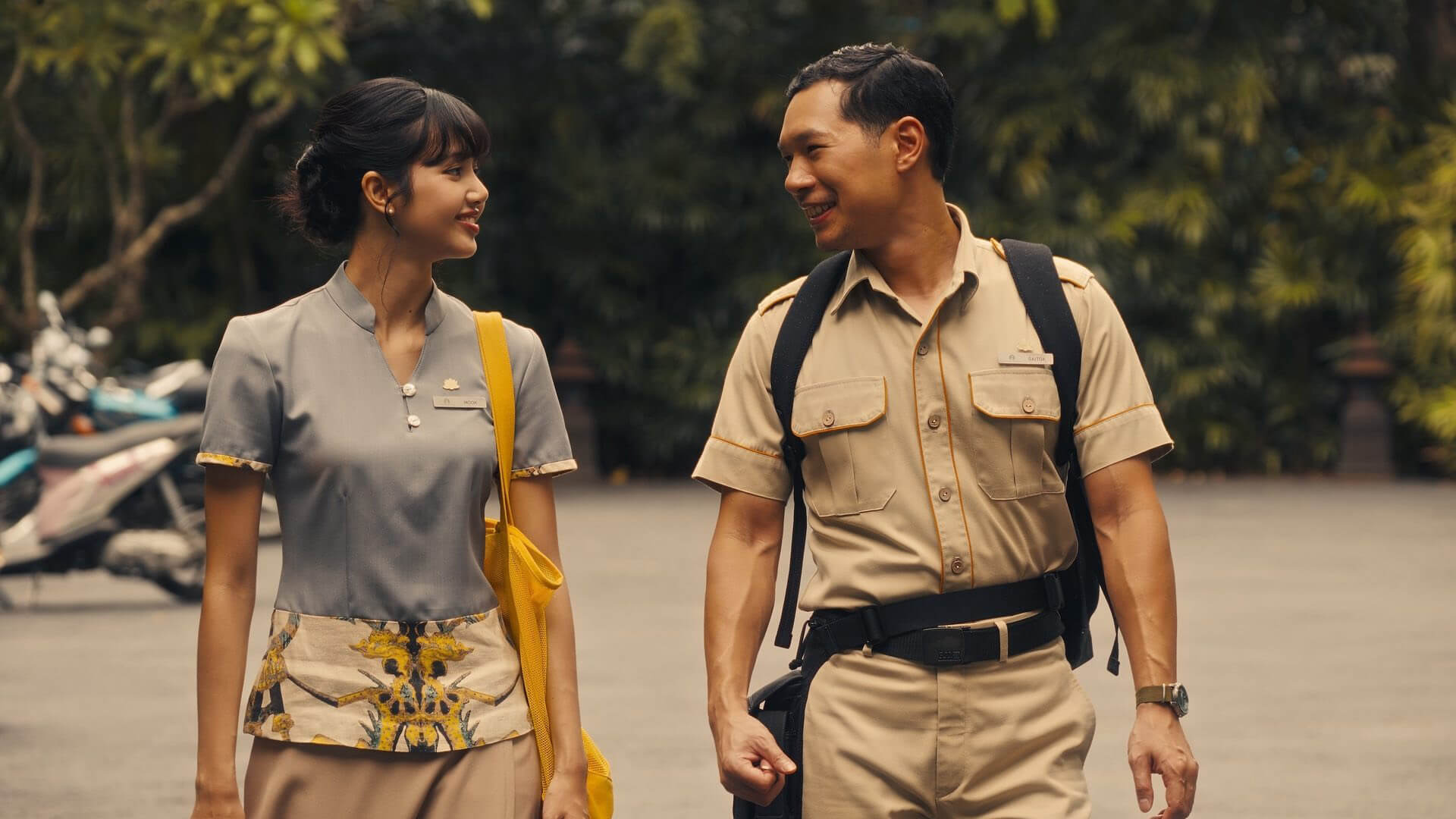 Mook and Gaitok walking and smiling at one another in The White Lotus.