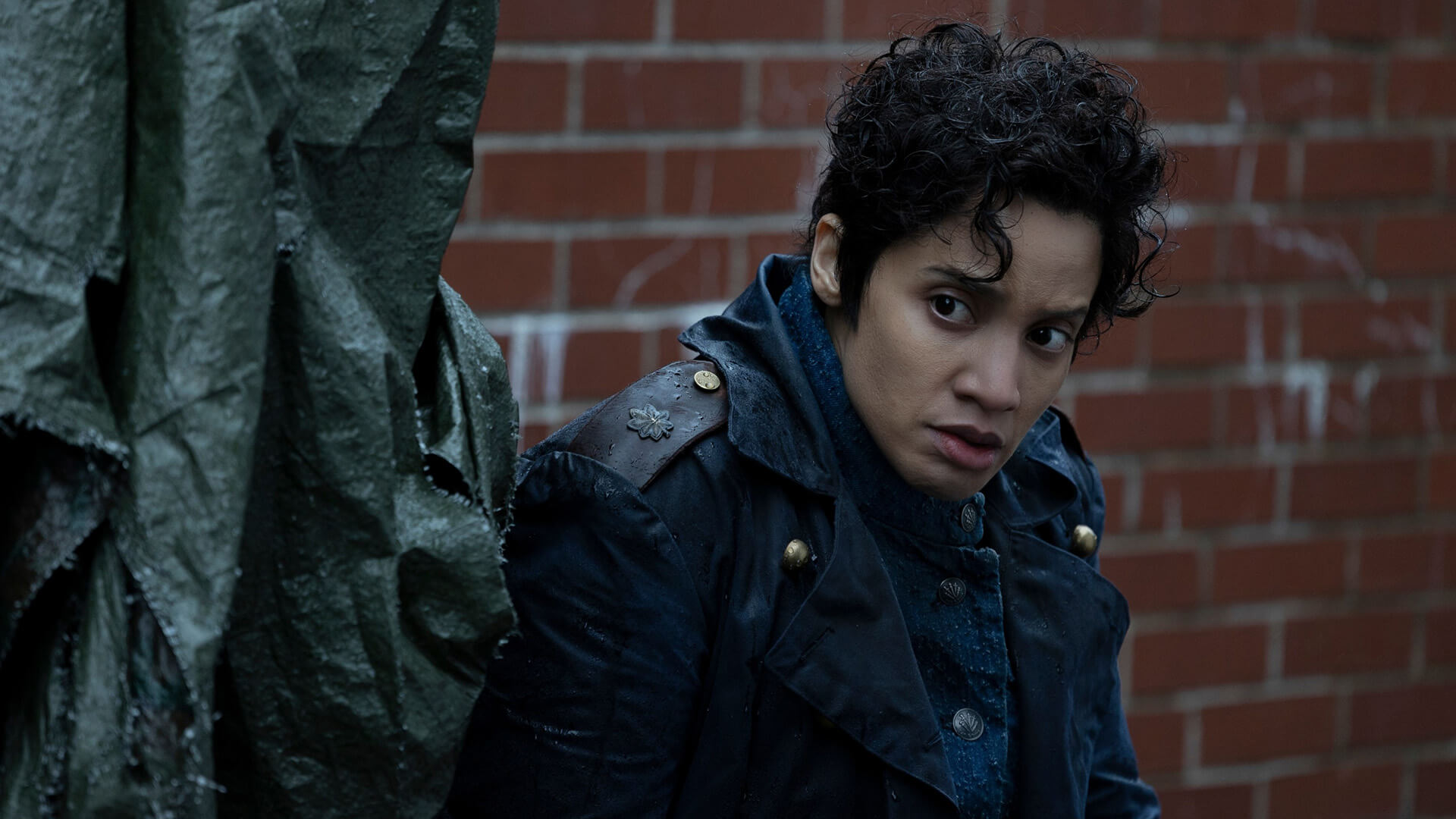 A female New Babylon Federation officer sitting in a corner in The Walking Dead: Dead City.