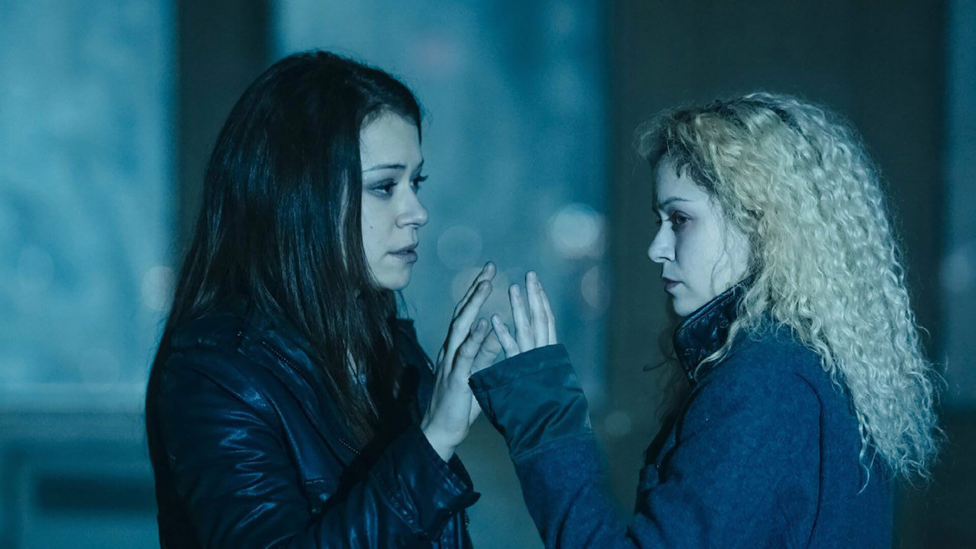 Sarah and Helena holding their hands up to one another in Orphan Black.