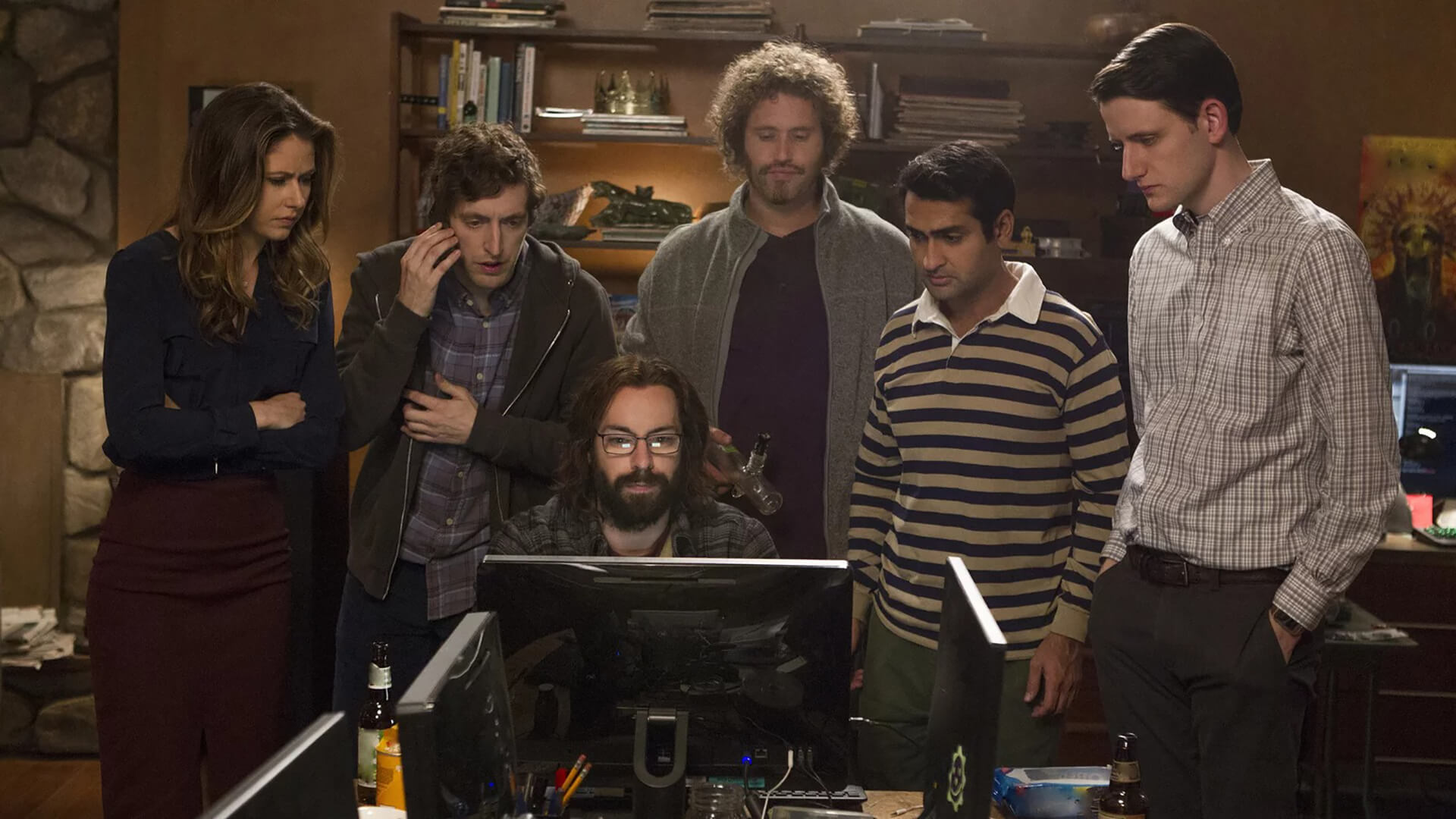 A group hovers around a man at a computer in Silicon Valley.
