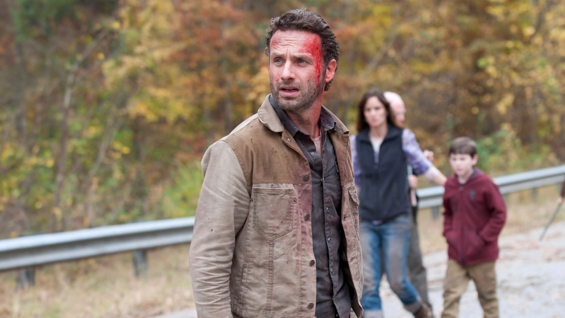 Rick with blood on his head, Lori and Carl walking behind him in The Walking Dead.