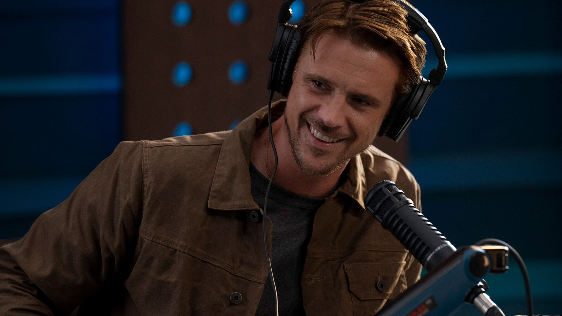 Brodie with a headset on his podcast in The Morning Show.