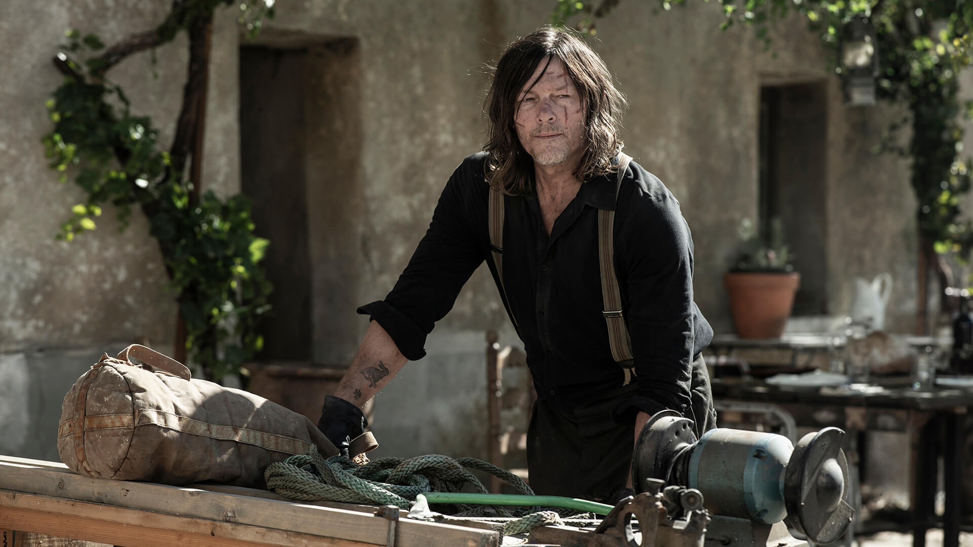 Daryl looking up from a table with items in The Walking Dead: Daryl Dixon.