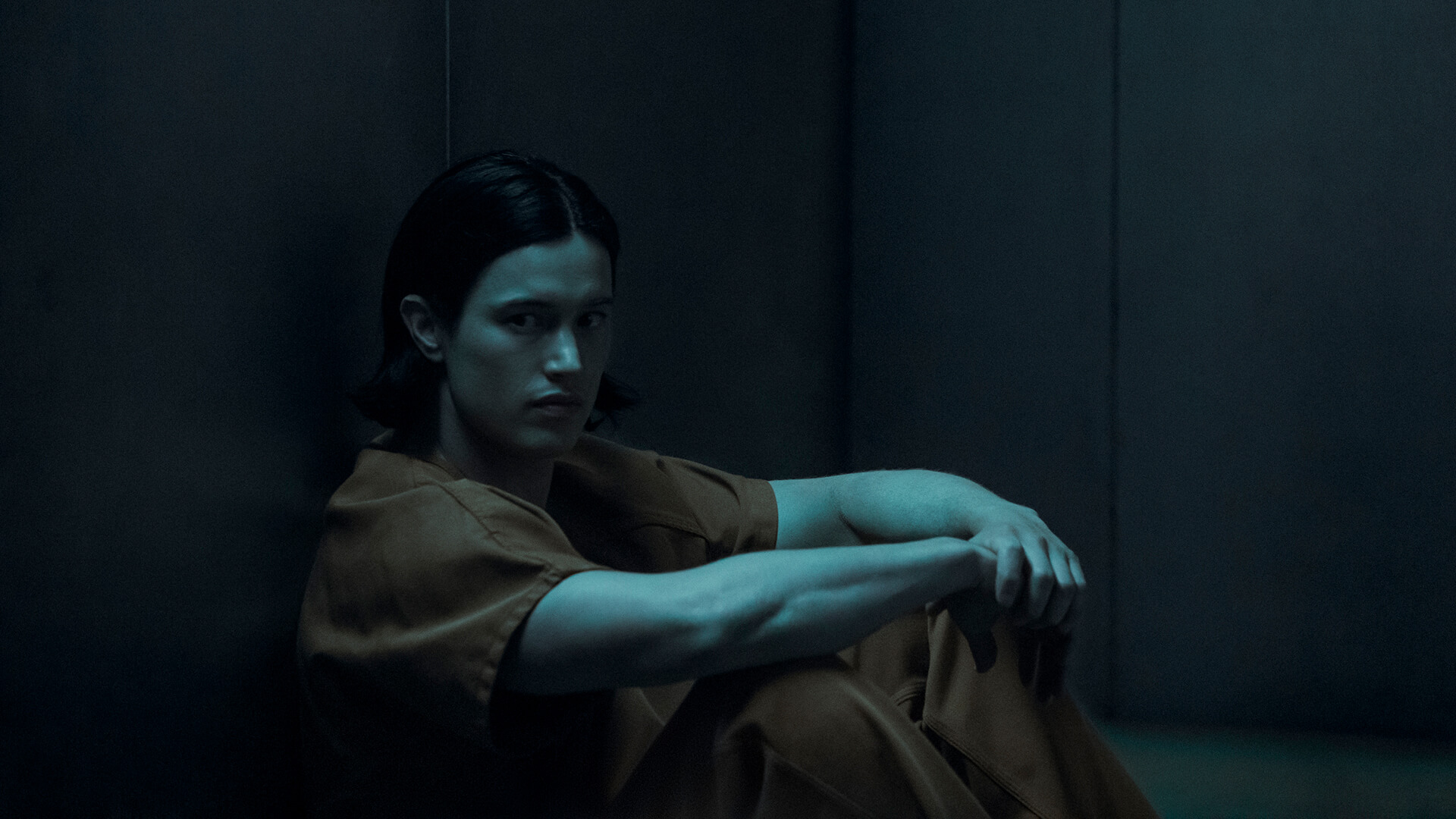 Jordan in male form sitting in a prison cell with an orange jumpsuit in Gen V.