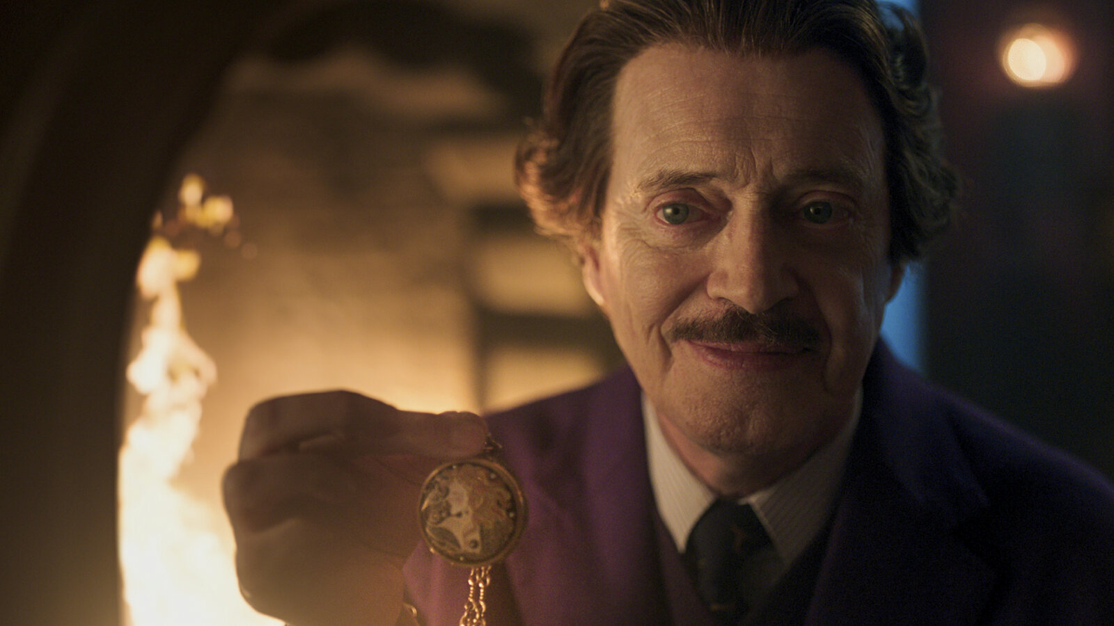 Barry Dort holding up his necklace by the fireplace in Wednesday.