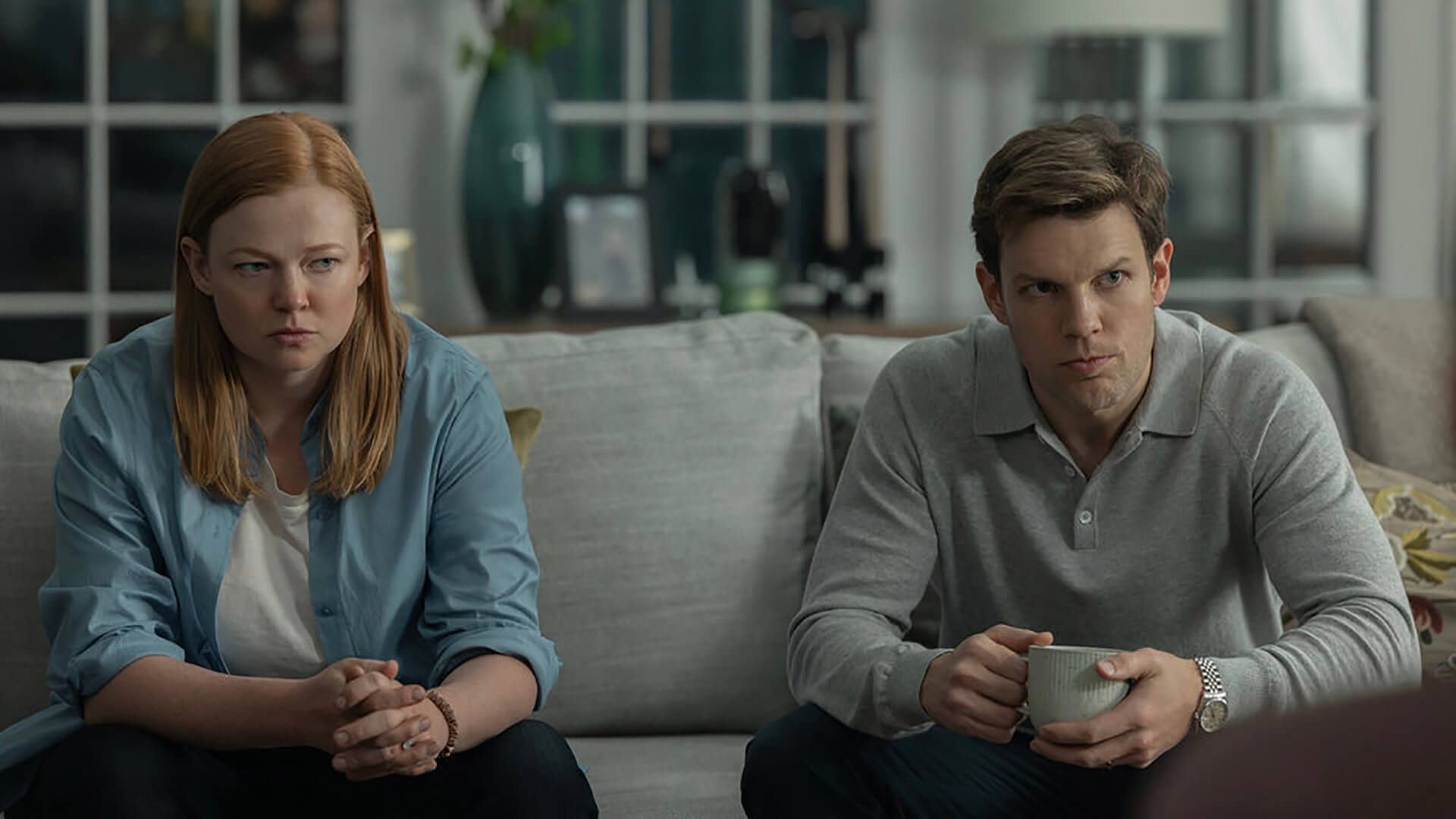 A woman and man on the couch looking upset in All Her Fault.