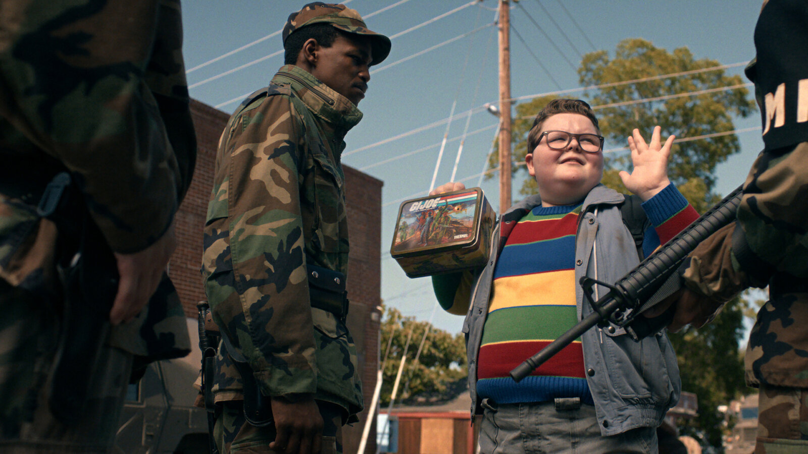 Derek with his hands up being approached by military men in Stranger Things.