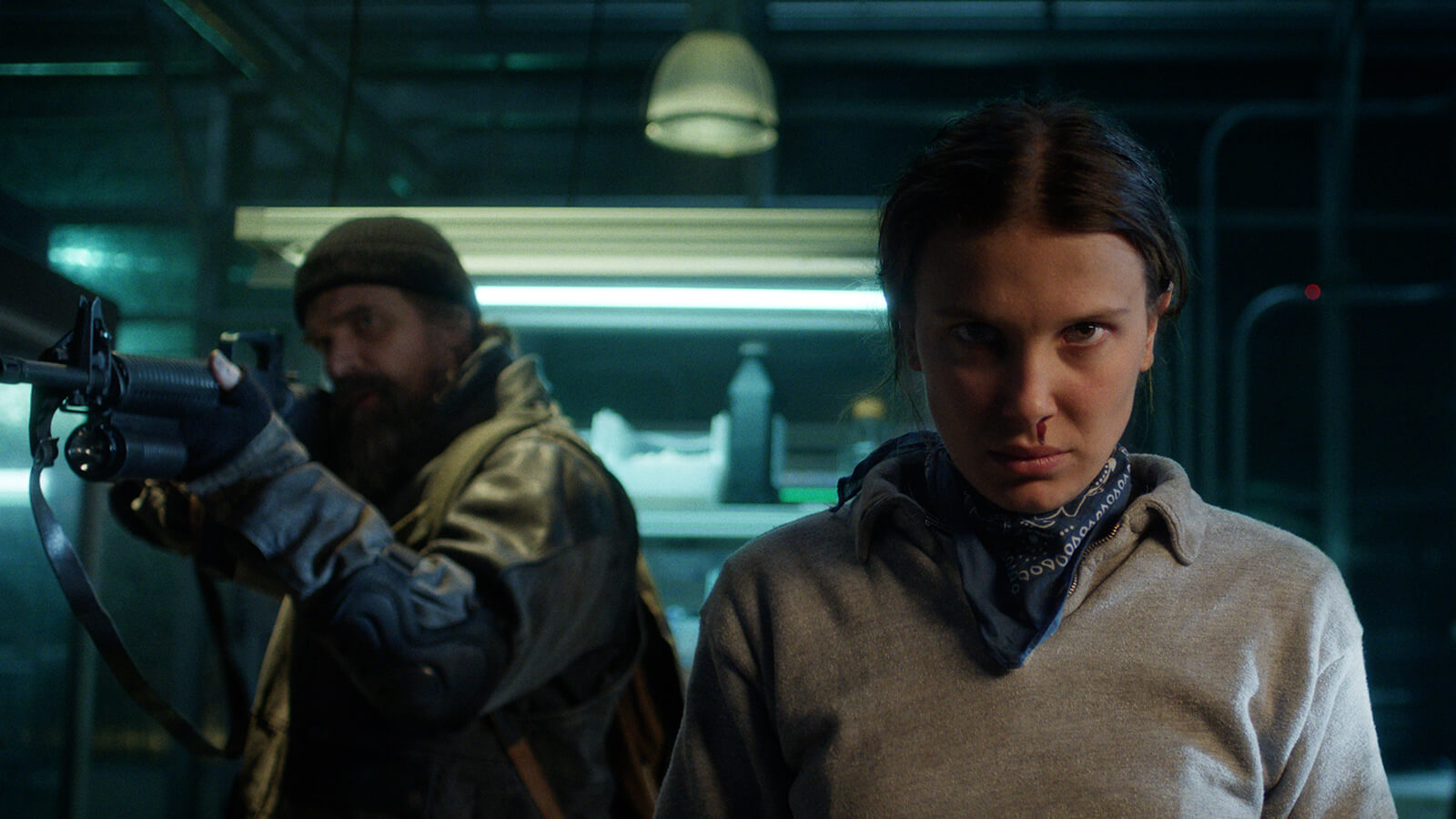 Eleven with blood coming from her nose, Hopper behind her with a gun in Stranger Things.