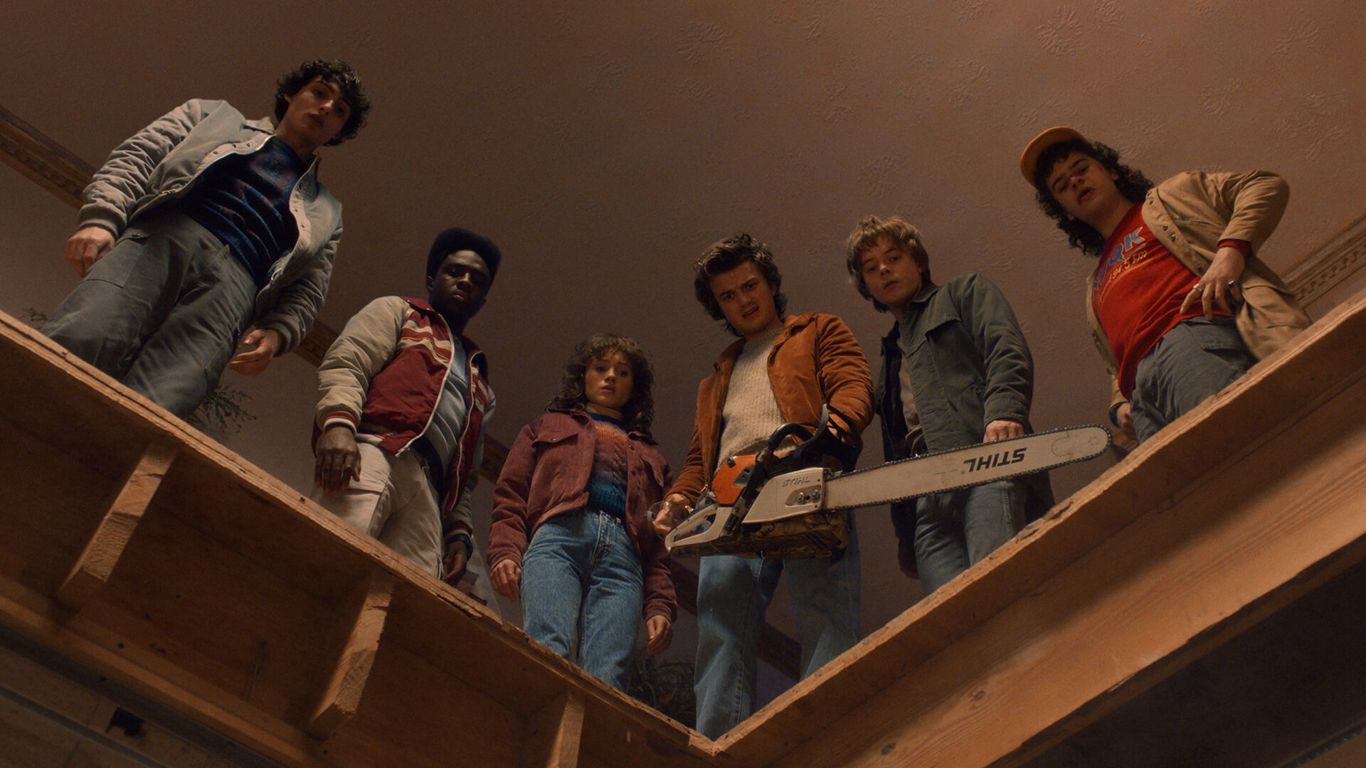 The kids standing and looking down into a hole in the floor in Stranger Things.