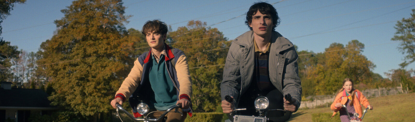 Will, Mike, and Holly riding their bikes in Stranger Things.