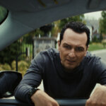 Nile standing at Aggie's car window in The Beast in Me.