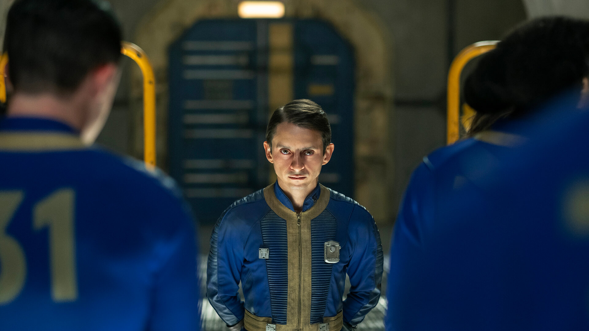 Norm standing in front of others in the vault in Fallout.