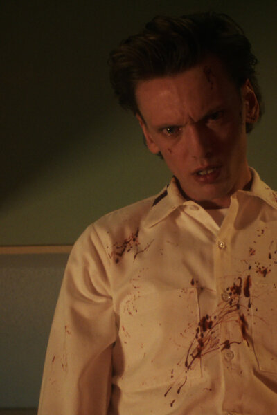 Henry in a white shirt looking angry and bloody in Stranger Things.