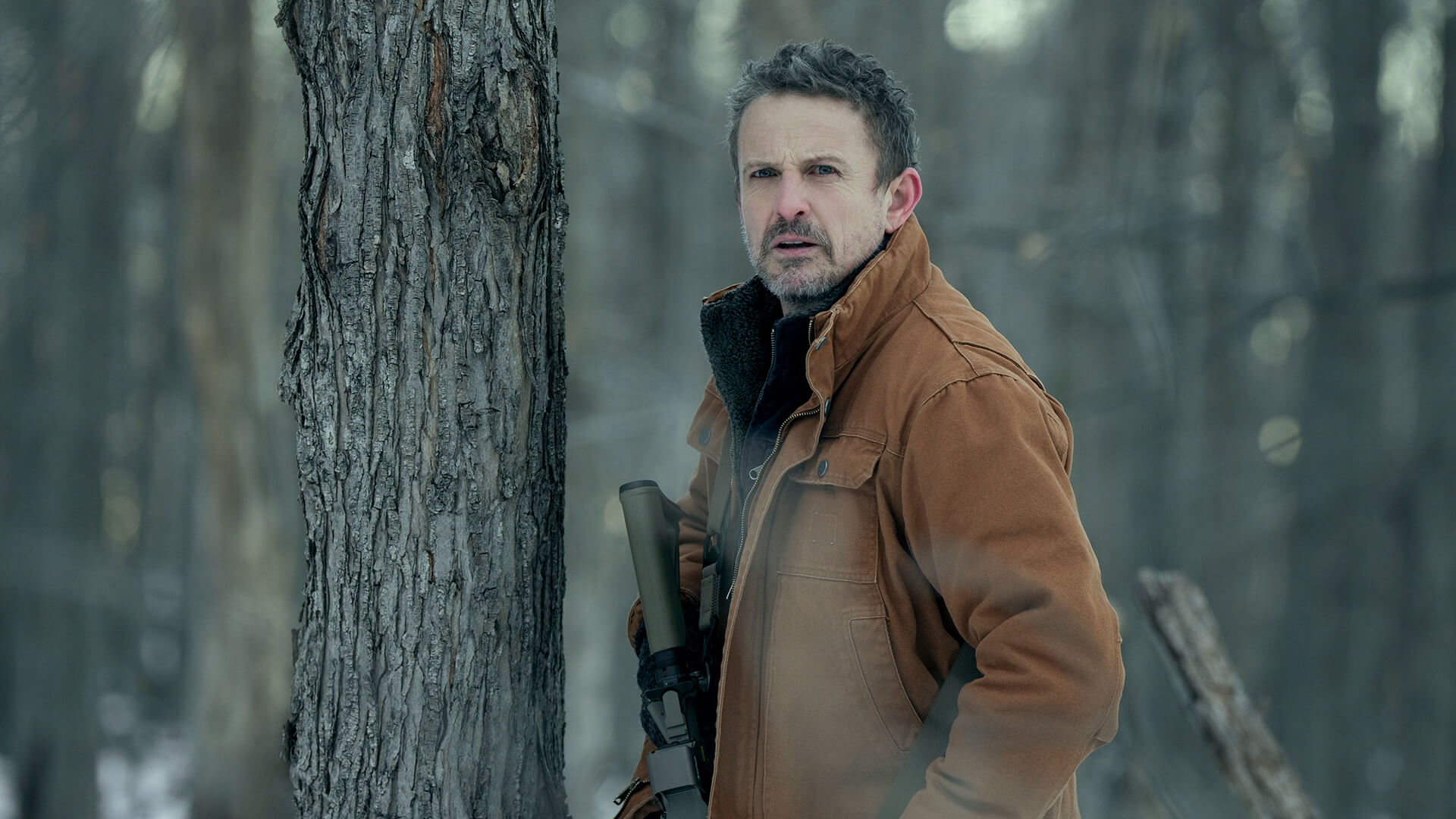 Adam standing by a tree outside in The Night Agent.