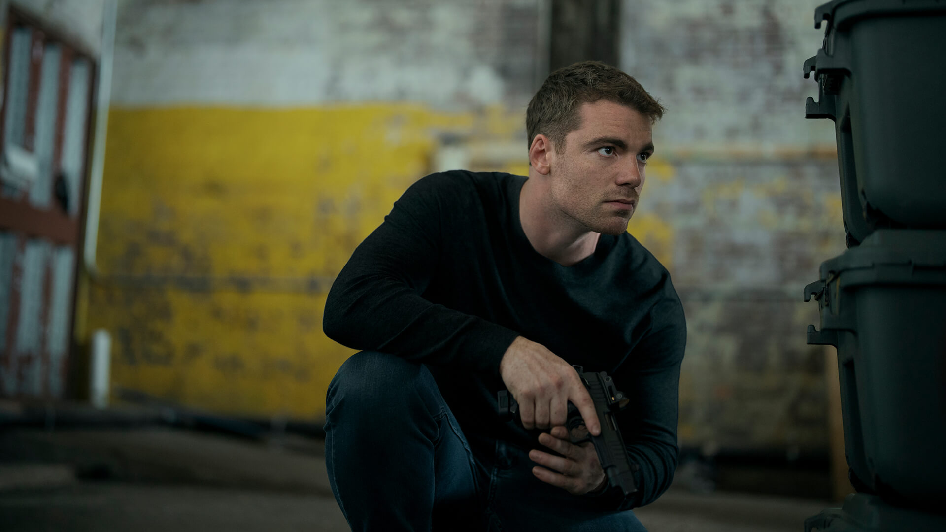 Peter crouched down with a gun in The Night Agent.