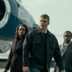 Peter with his handlers standing by a plane in The Night Agent.