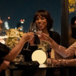 Three women clinking glasses on an outdoor patio in Imperfect Women.