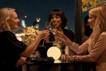 Three women clinking glasses on an outdoor patio in Imperfect Women.