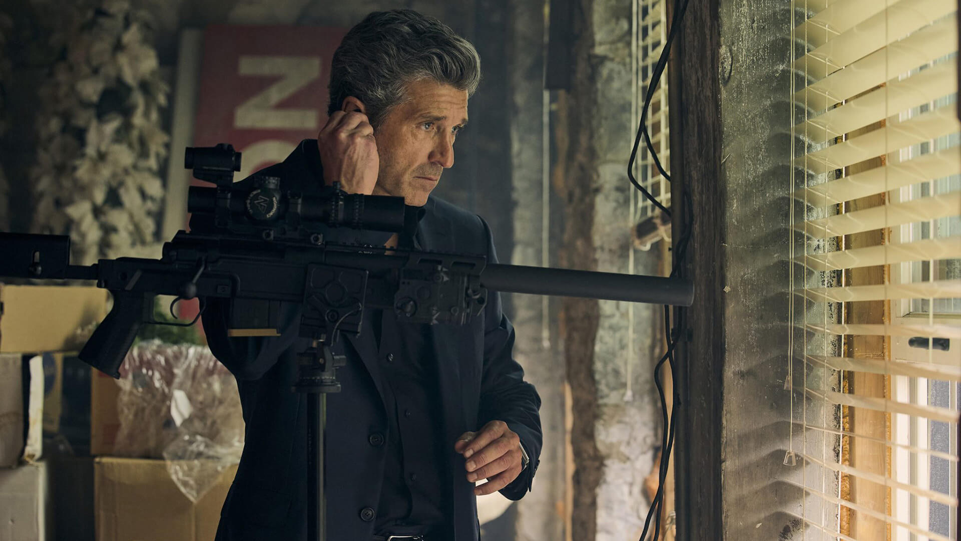 Angelo in Memory of a Killer standing by a window with a gun and scope.