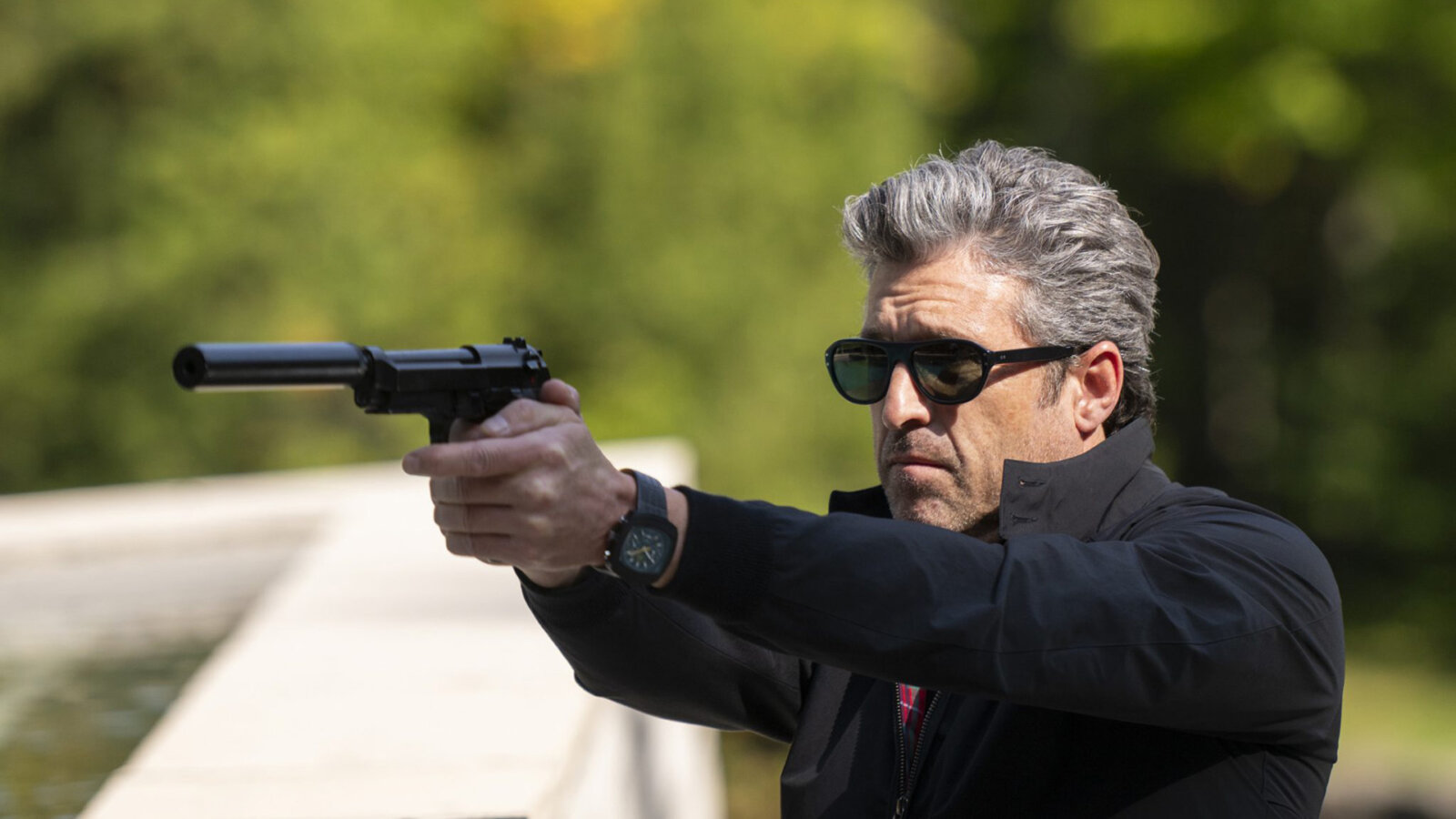 Angelo wearing sunglasses outside pointing a gun in Memory of a Killer.