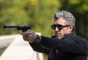 Angelo wearing sunglasses outside pointing a gun in Memory of a Killer.