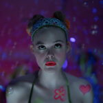 Margo in make-up o a psychadelic background in Margo's Got Money Troubles.