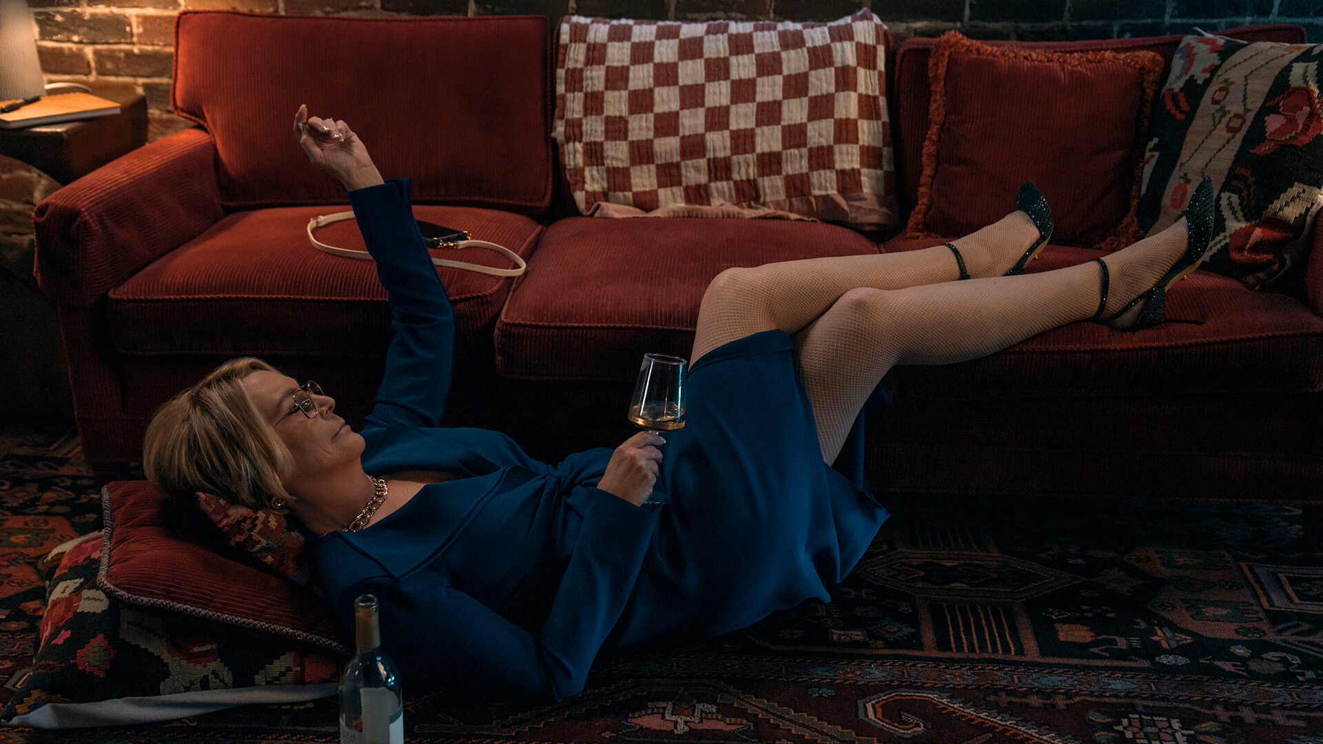 Dorothy lying on the floor smoking with a glass of wine in Scarpetta.