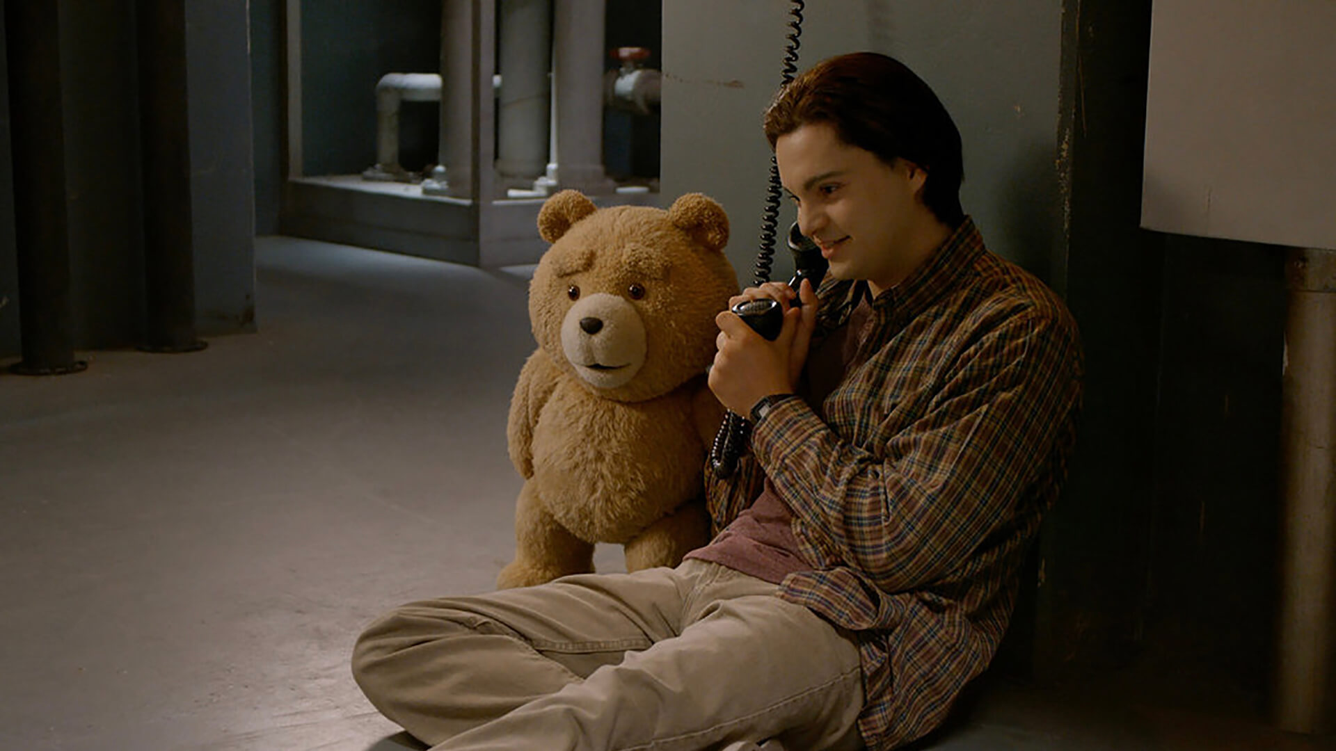 John and Ted sitting on the floor on a phone in Ted.