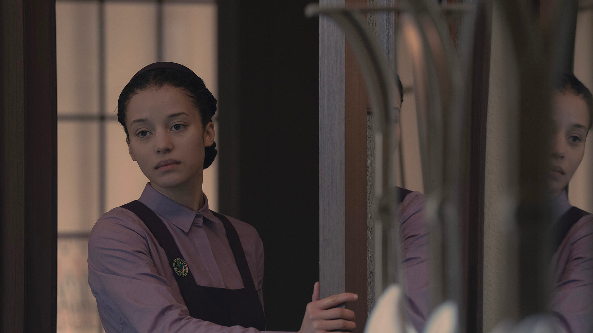 Agnes standing by a mirror in The Testaments