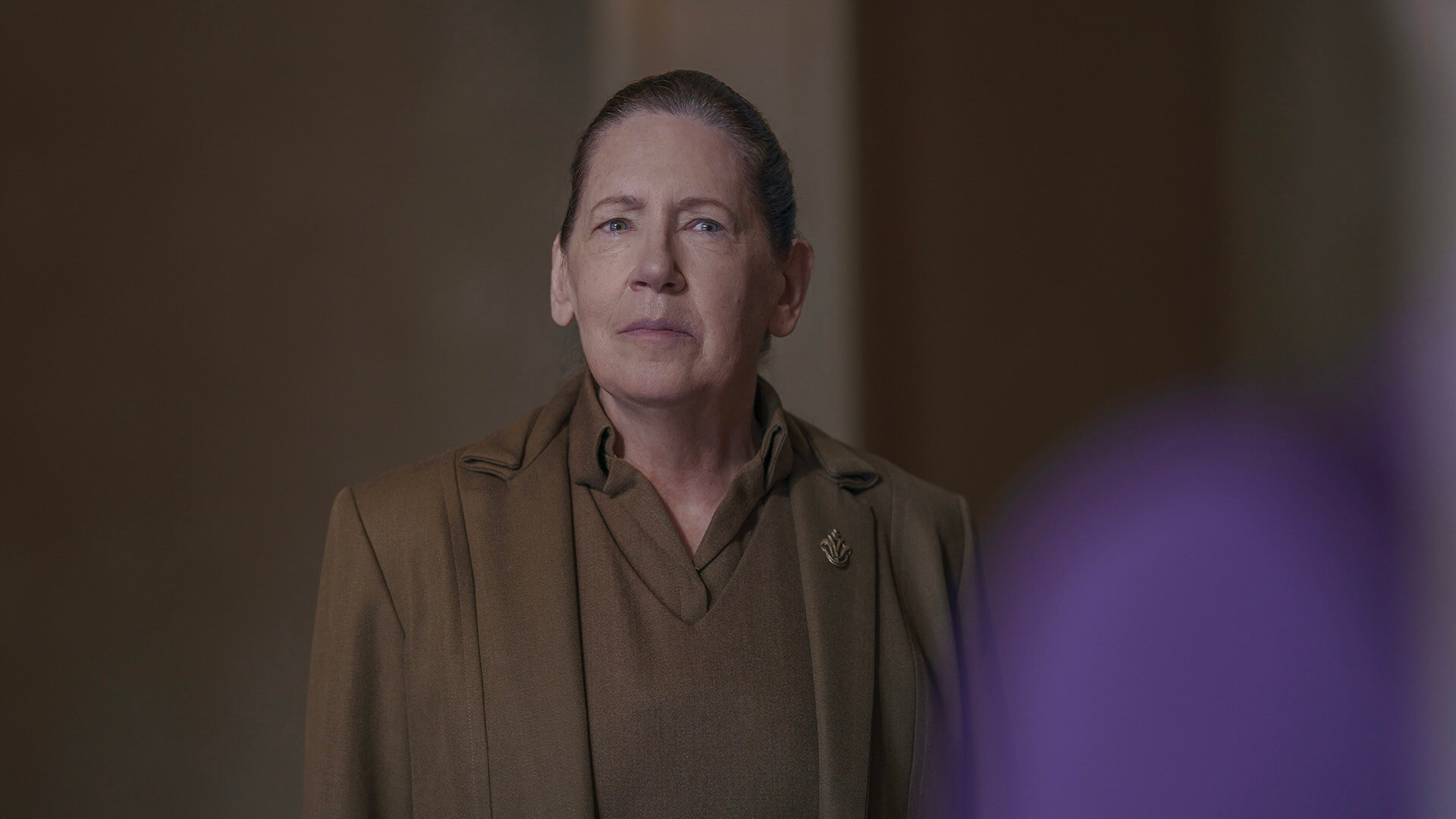 Aunt Lydia looking curiously in The Testaments.