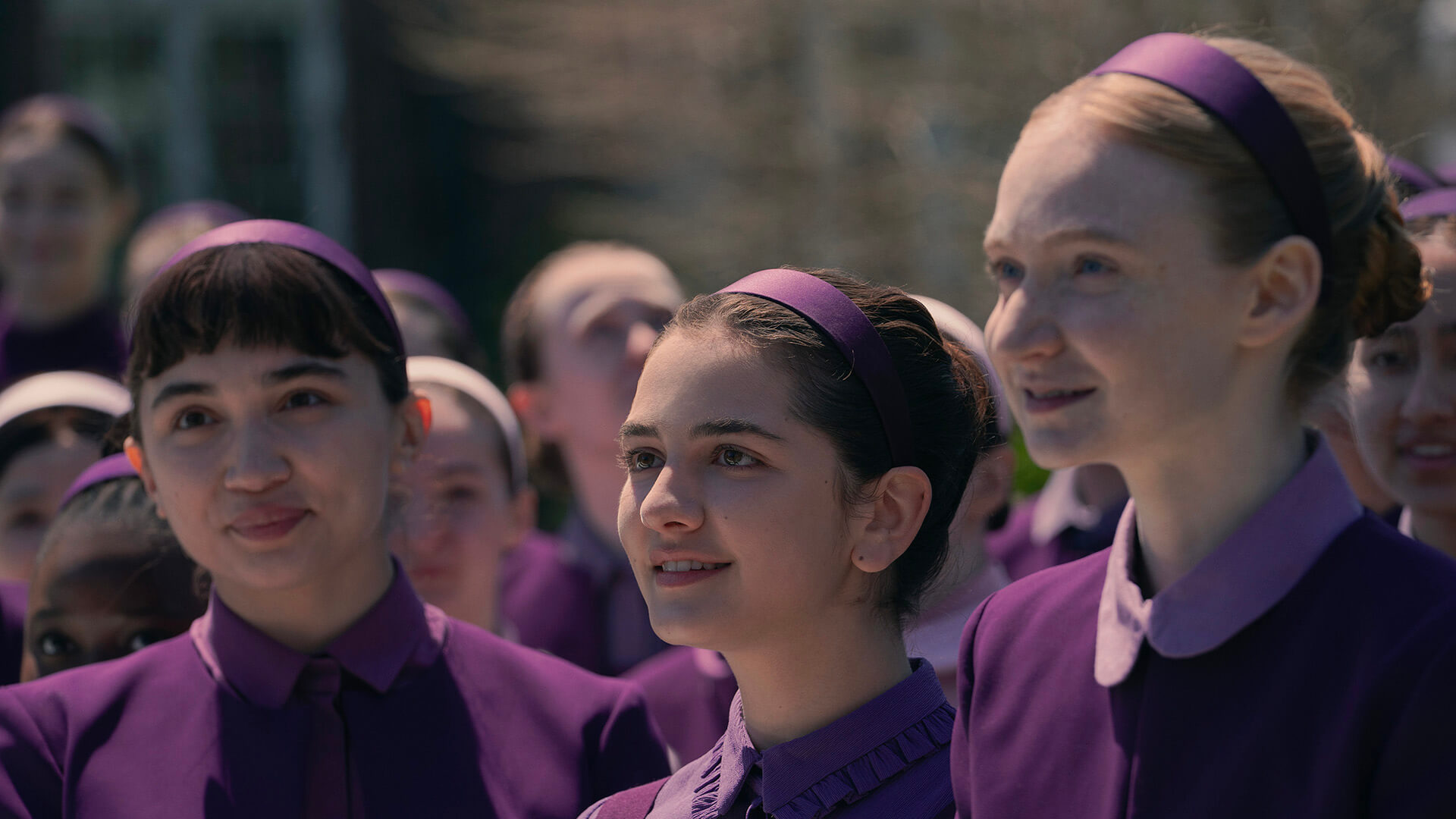 Three girls in plum uniforms in The Testaments.