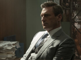 Coop in a suit in his office thinking in Your Friends & Neighbors.