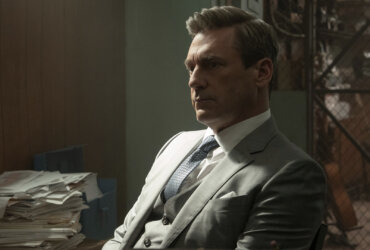 Coop in a suit in his office thinking in Your Friends & Neighbors.