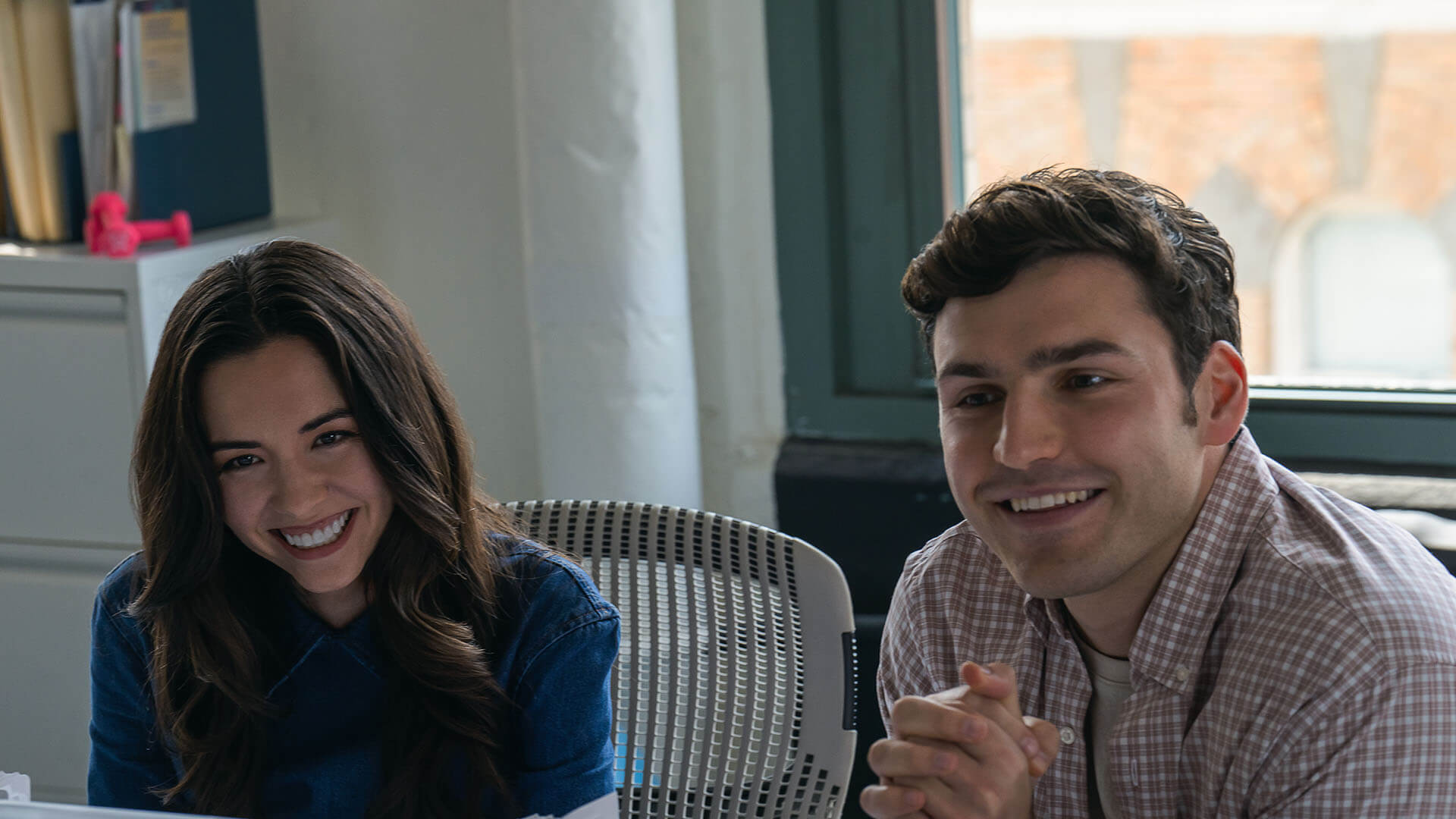 Geri and Rudy in the office smiling in Maximum Pleasure Guaranteed.