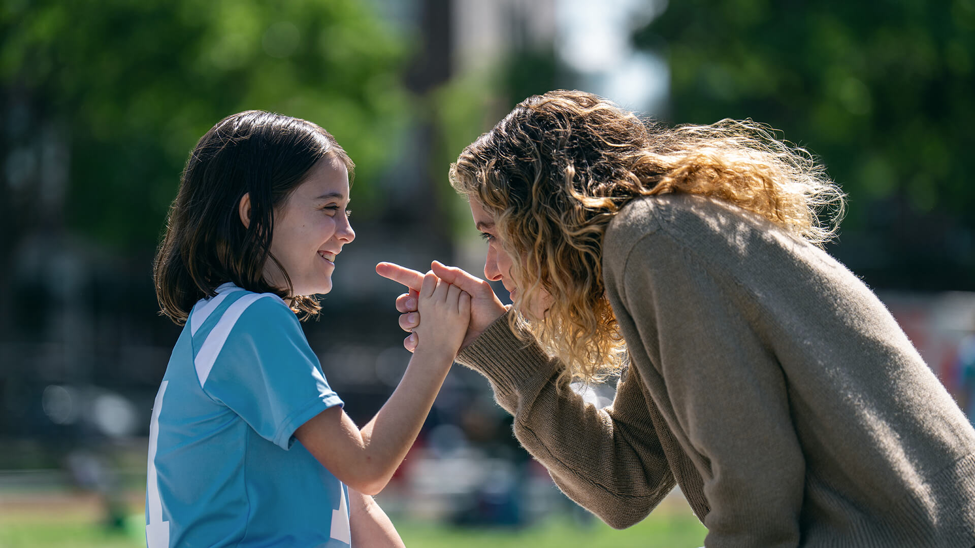 Paula pointing a finger at her daughter Hazel and smiling on the soccer field in Maximum Pleasure Guaranteed.