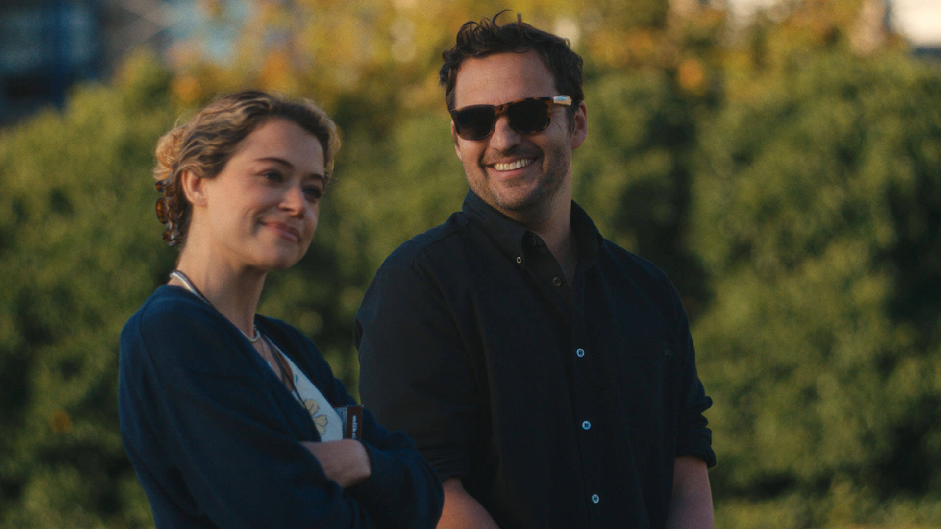 Paula with her arms folded smiling, Karl beside her smiling in Maximum Pleasure Guaranteed.