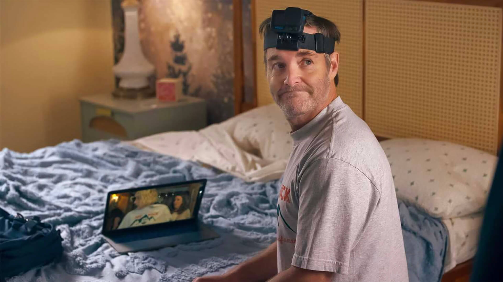 Jack sitting on the bed with a GOPro on his head and his laptop in front of him in The Four Seasons.