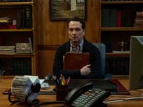 Tom sitting in his office clutching a folder in Widow's Bay.