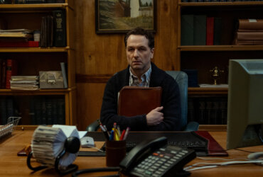 Tom sitting in his office clutching a folder in Widow's Bay.
