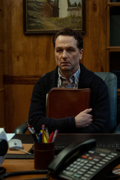 Tom sitting in his office clutching a folder in Widow's Bay.