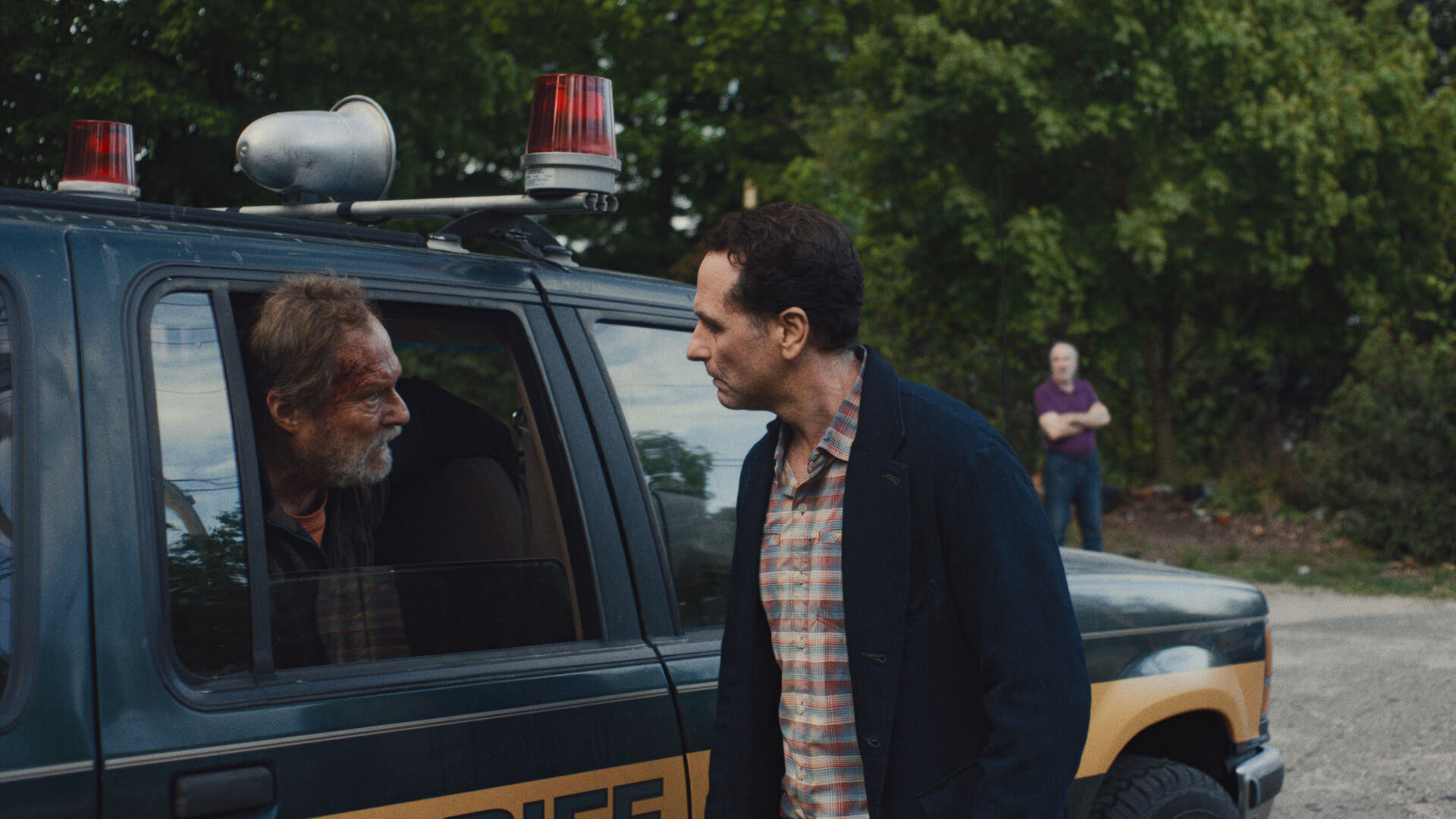 Tom standing outside a car talking to Wyck who is in the car in Widow's Bay.
