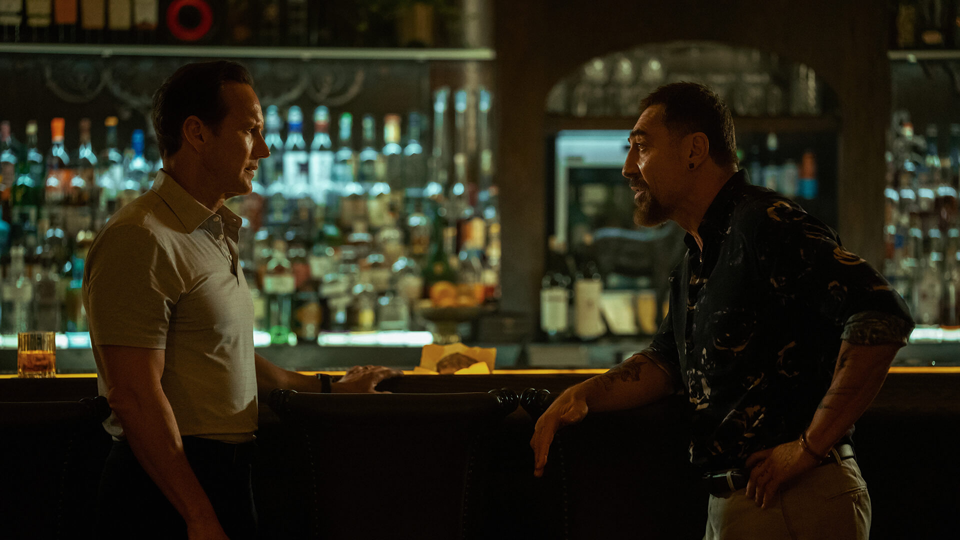 Tom and Max sitting across from one another at a bar in Cape Fear.